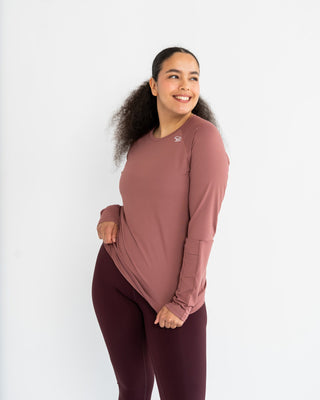Woman wearing a mauve long-sleeve top and leggings on a white background