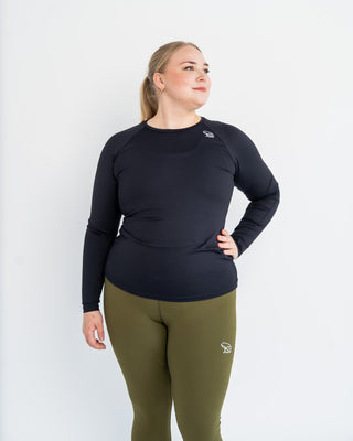 Person wearing a black long-sleeve top and green leggings on a white background