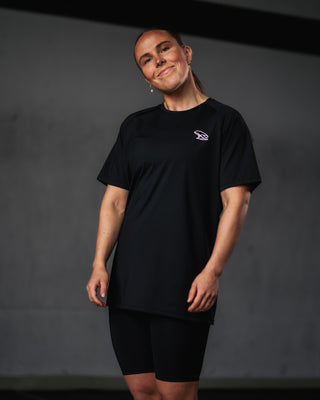 Woman wearing a black Népra outfit with a white logo on a dark background