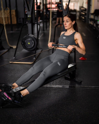 Woman exercising on a rowing machine in a gym setting